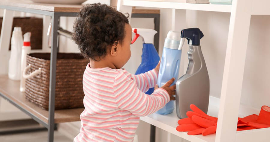 A young child touches cleaning supplies.